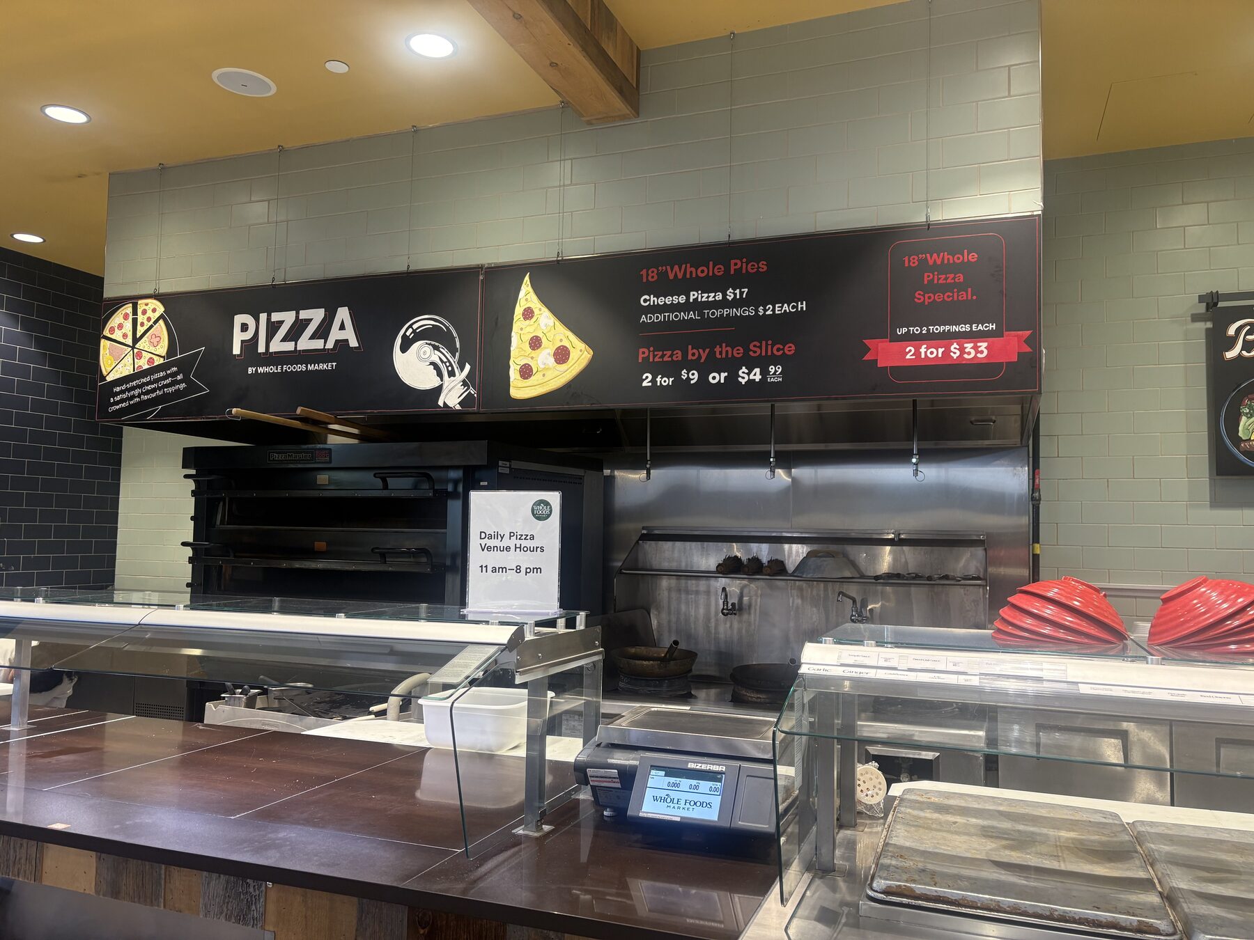 Hand-illustrated pizza department signage installed above a counter
